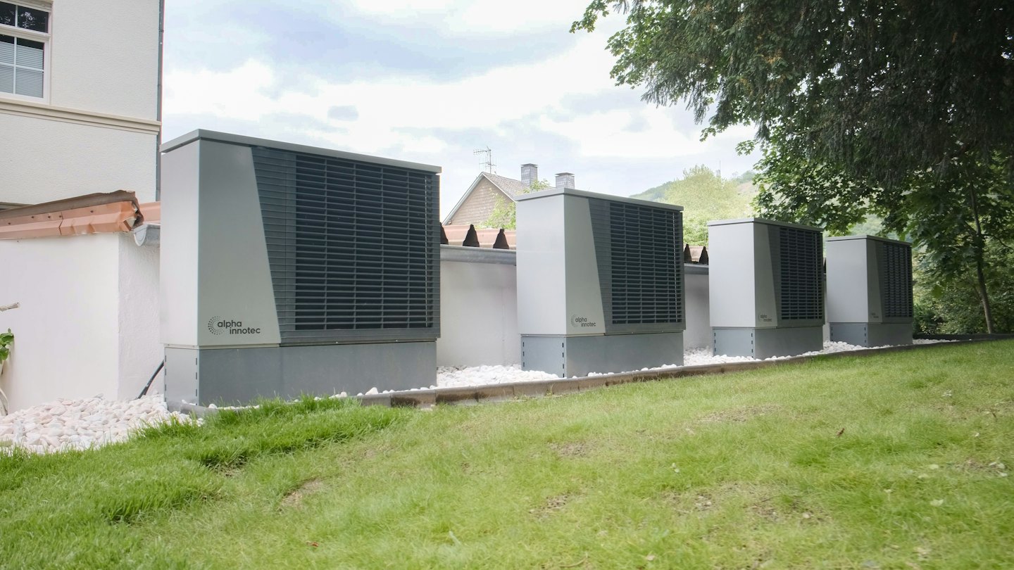 Quattro moderne unità di pompa di calore grigie installate all'esterno.